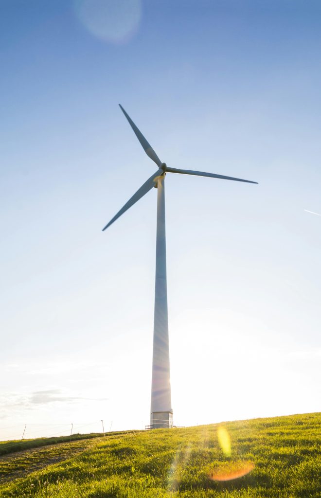 pexels-photo-414928-414928 A wind turbine on a grassy hill with a clear blue sky symbolizes renewable energy.