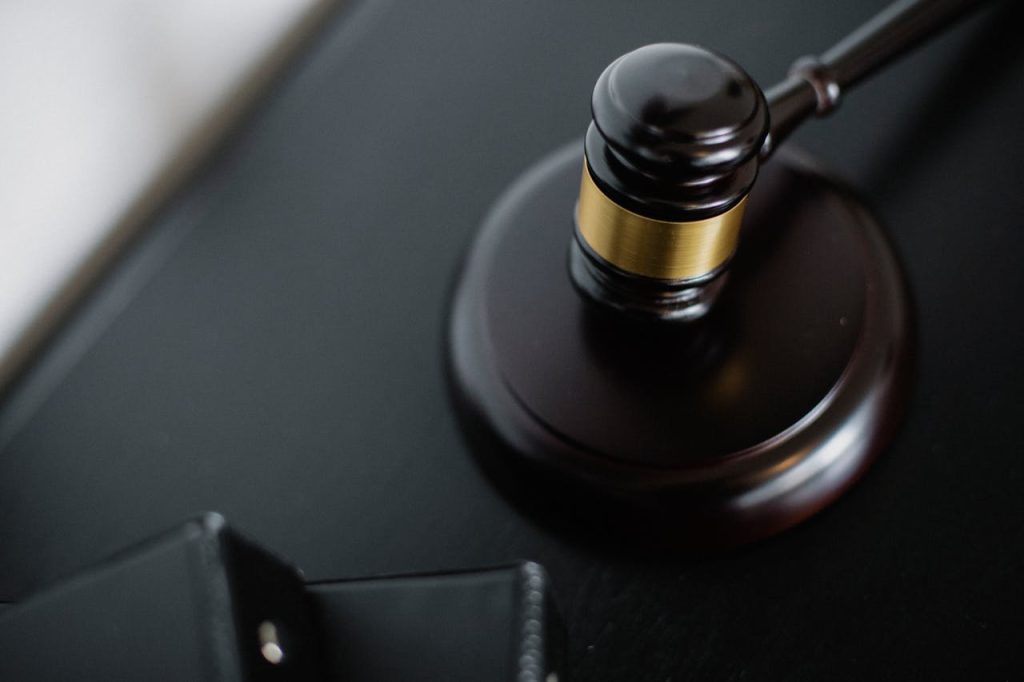 pexels-photo-5668481 Close-up of a wooden judge's gavel on a black desk, symbolizing justice and law.